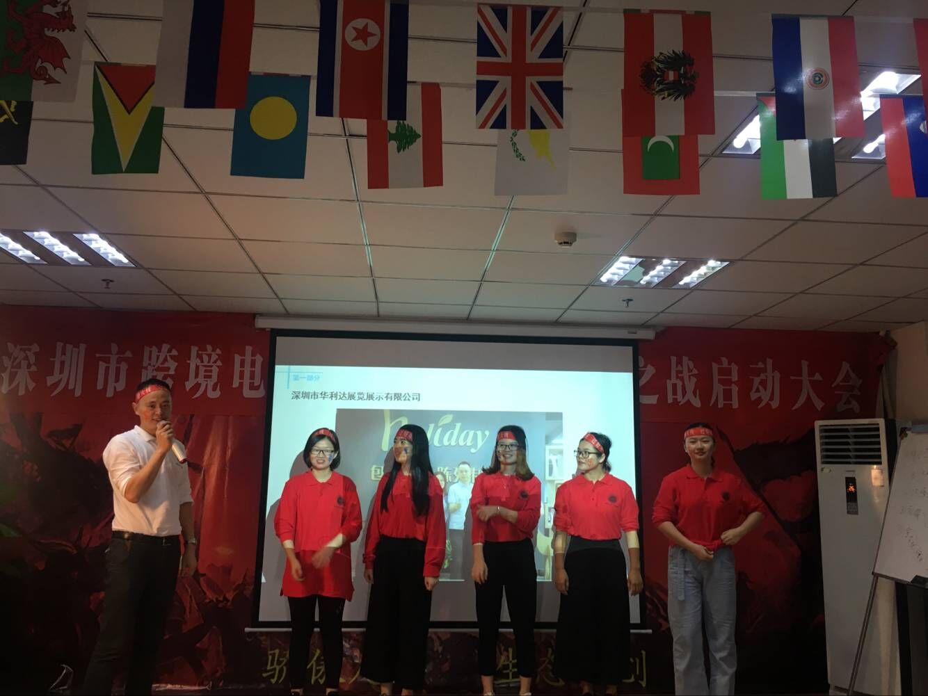 Holidaypacfactory cross-border e-commerce kickoff conference team in red uniforms with international flags at Shenzhen training event