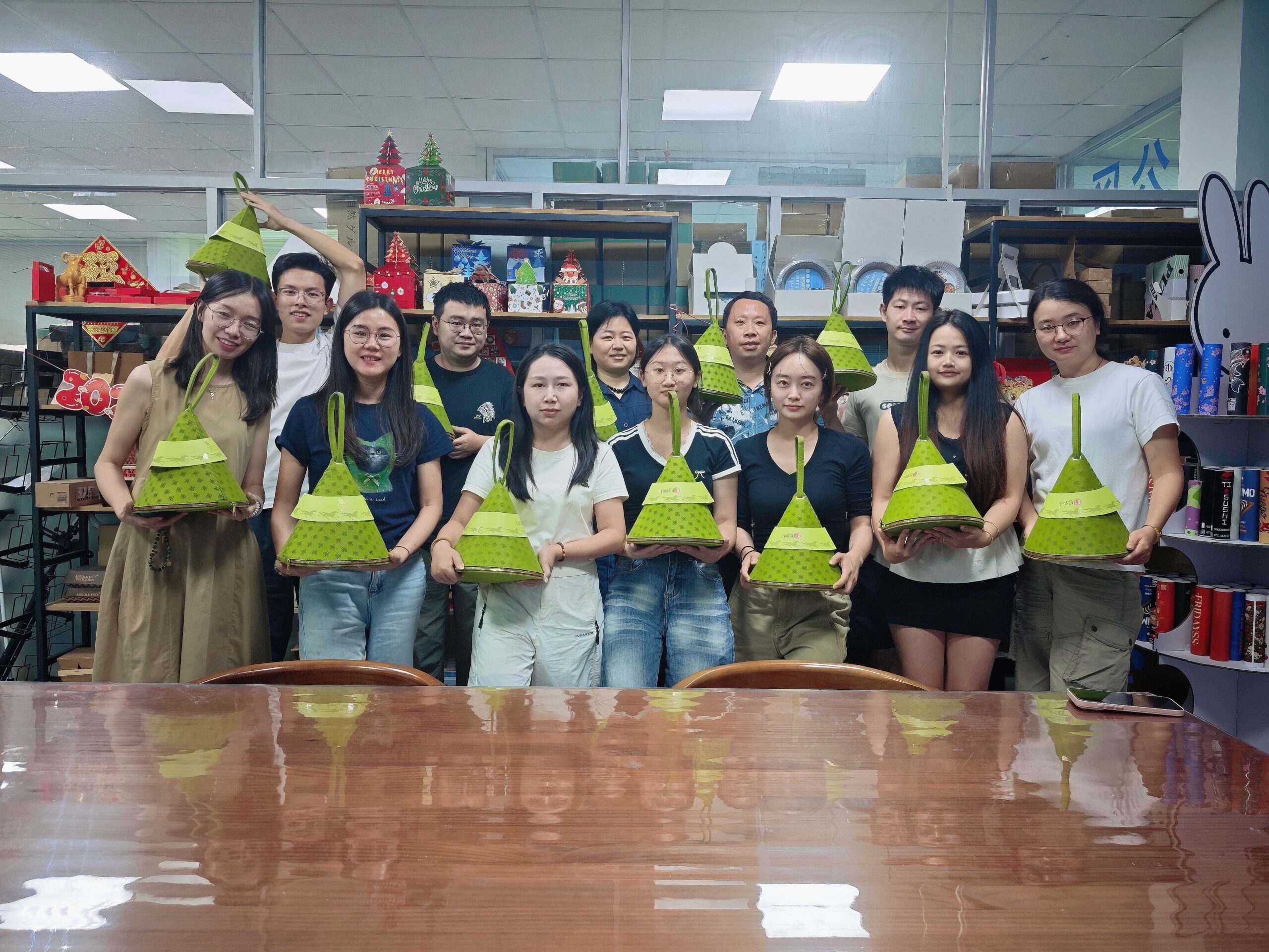 Holidaypac team members smiling and showing custom zongzi packaging gift bags to celebrate Duanwu Festival together