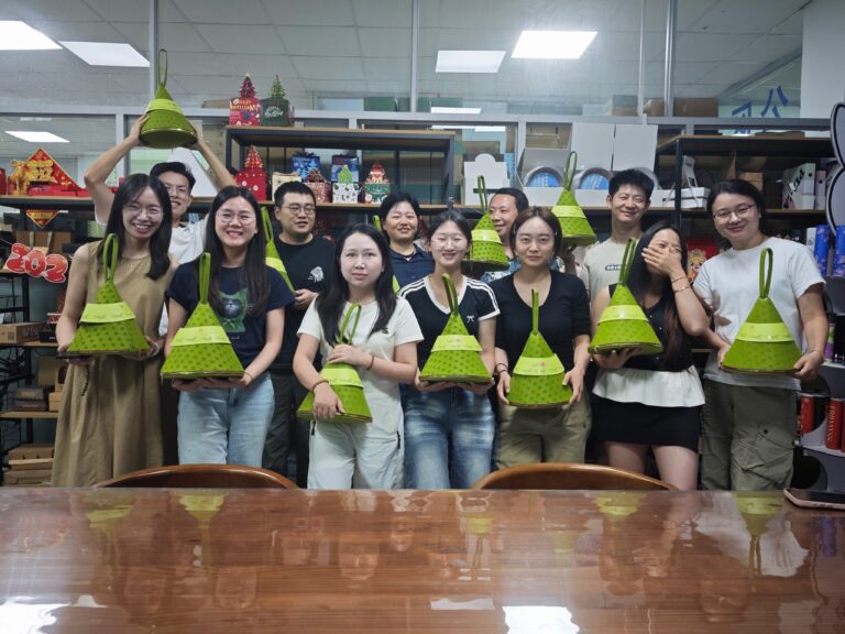 Holidaypac team members smiling and showing custom zongzi packaging gift bags to celebrate Duanwu Festival together