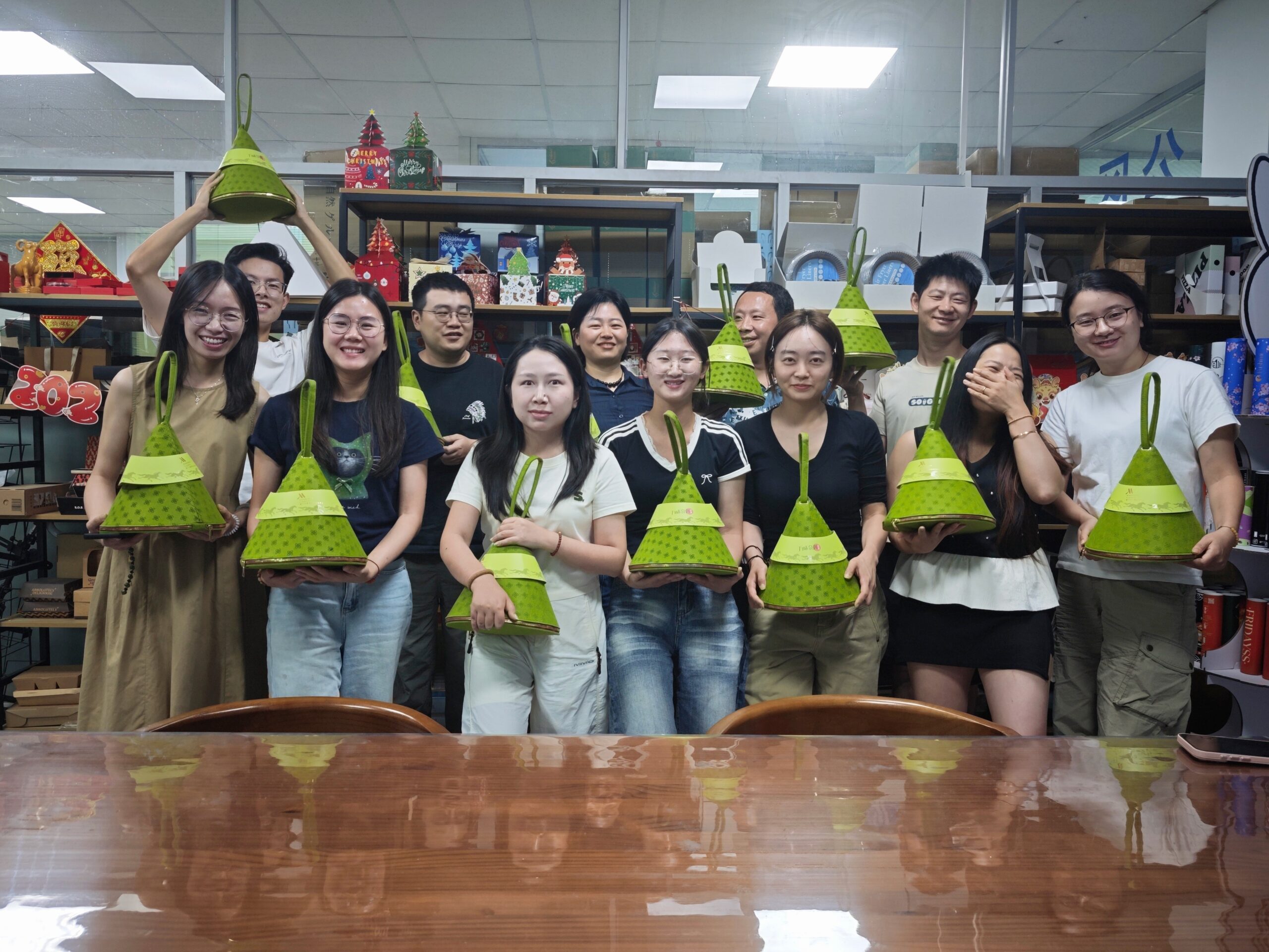 Holidaypac employees holding handmade green zongzi-shaped paper gift bags during the Dragon Boat Festival team-building event