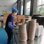 Factory worker packing square air fryer paper liners on production line at Holidaypacfactory